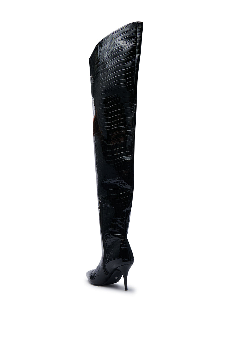The AZALEA WANG HALINA BLACK CROC STILETTO BOOT is displayed against a white background, featuring a pointed toe silhouette and stiletto heel, with its glossy faux crocodile leather finish extending over the knee.