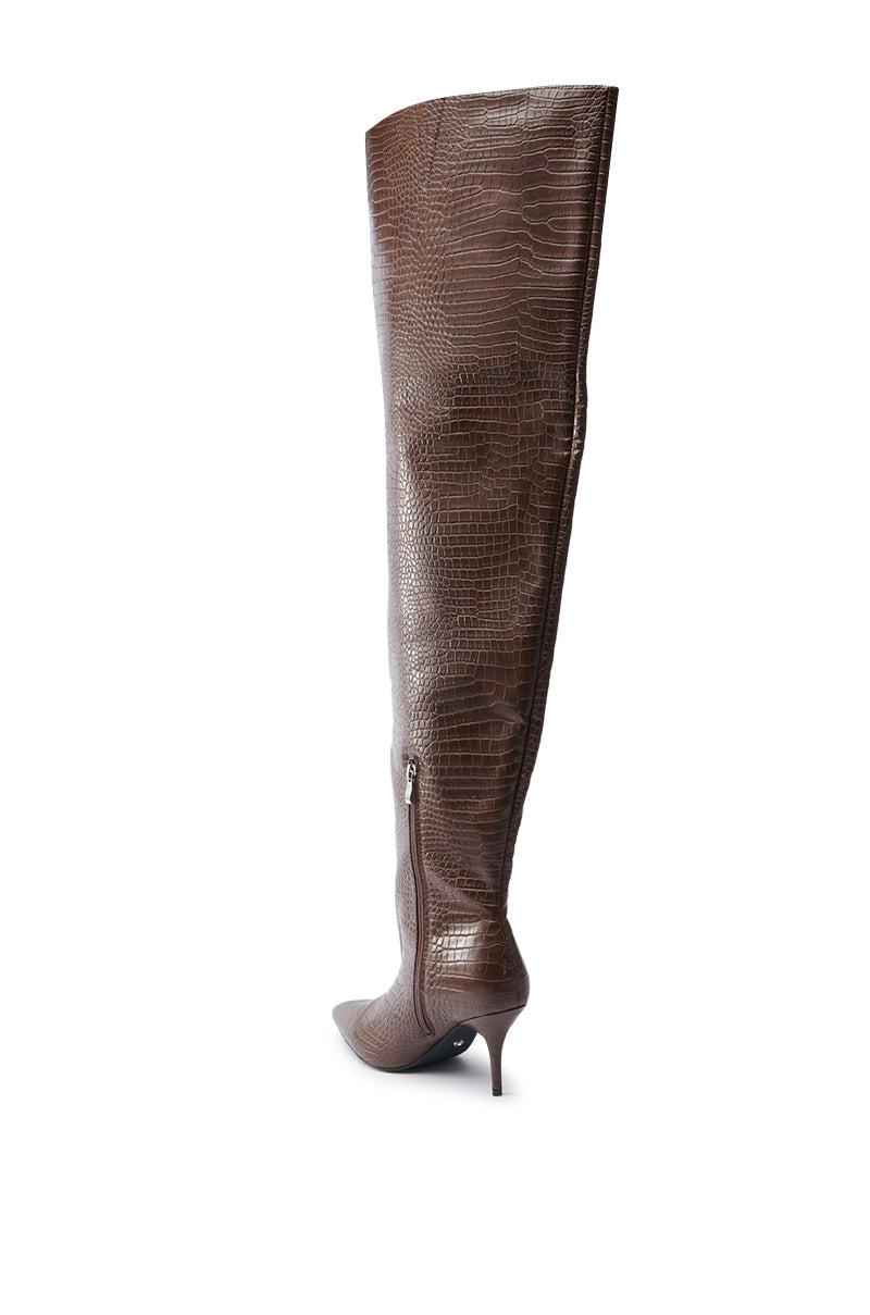The AZALEA WANG HALINA BROWN CROC STILETTO BOOT is displayed against a white background, featuring a thigh-high shaft, pointed toe, side zipper, and slender stiletto heel in faux crocodile leather.