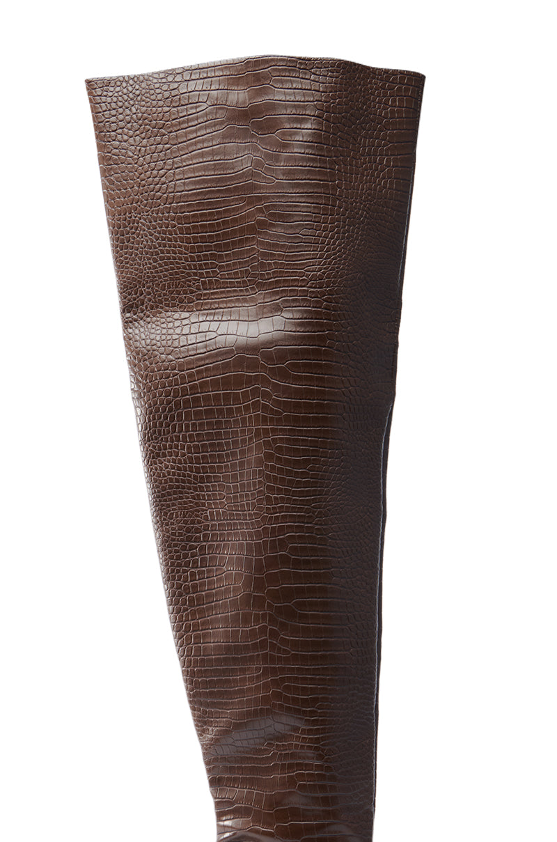 The AZALEA WANG HALINA BROWN CROC STILETTO BOOT is a tall, brown faux crocodile leather boot with a textured crocodile pattern and thigh-high shaft that enhances an elongated silhouette, complete with a sleek, glossy finish.