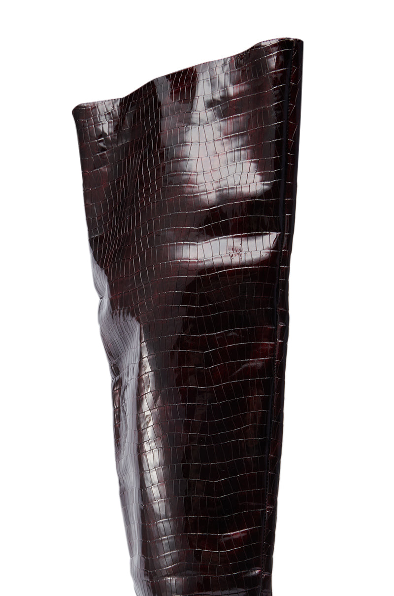 A close-up of the AZALEA WANG HALINA BURGUNDY CROC STILETTO BOOT, featuring a tall, glossy, faux crocodile finish in deep burgundy and a thigh-high shaft that showcases the material’s texture and shine.