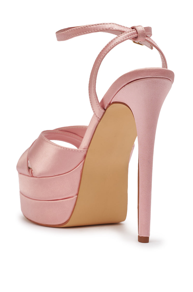 A rear view of the AZALEA WANG HALLADAY PINK SATIN PLATFORM STILETTO SANDAL, featuring an ankle strap and peep-toe design, displayed on a white background. 9