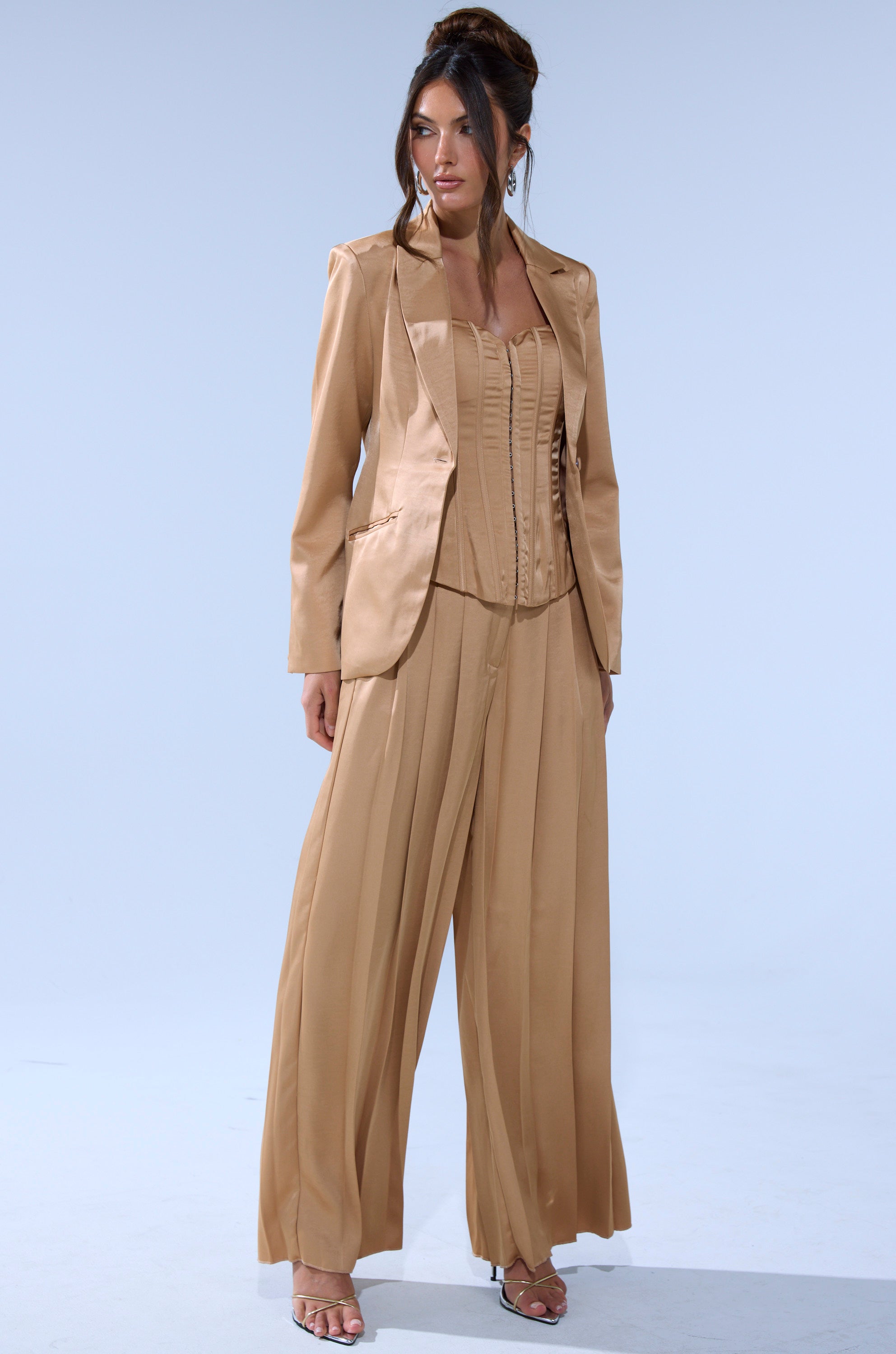 A woman wears the HANSEL MOCHA SATIN CORSET with a sweetheart neckline, paired with a matching tan blazer and wide-leg trousers. Her dark hair is styled up, and she finishes the elegant look with strappy sandals against a light background.