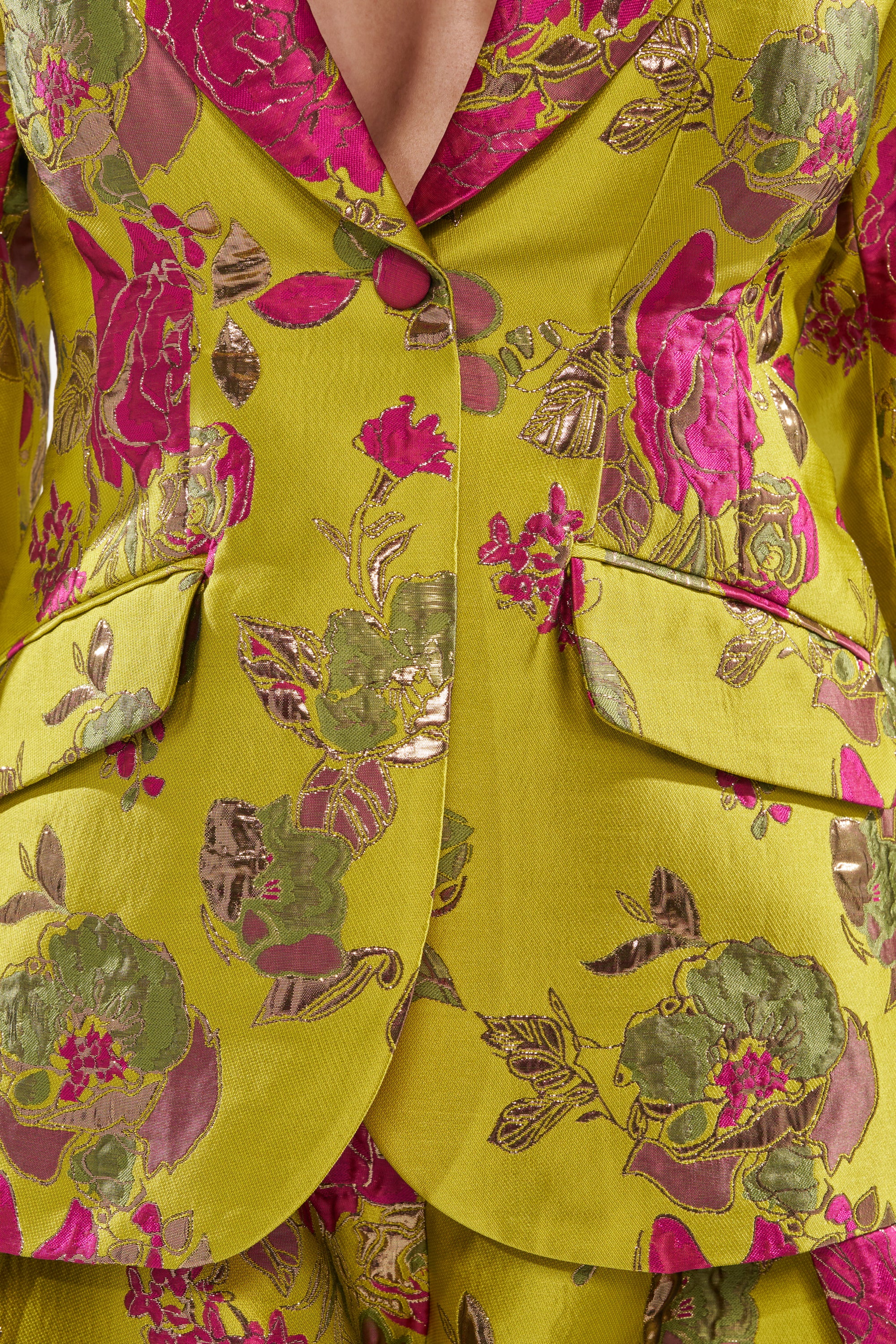 Close-up of the BUY MYSELF FLOWERS BROCADE BLAZER IN LIME, featuring metallic pink and gold floral embroidery, flap pockets, a deep neckline, and vibrant textured fabric with detailed rose patterns.