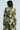 Against a neutral background, the person dons a stylish black suit featuring the BUY MYSELF FLOWERS BROCADE BLAZER, which showcases a striking yellow floral pattern. The ensemble is complemented by wide-leg trousers and adorned with subtle metallic details for an added touch of elegance.