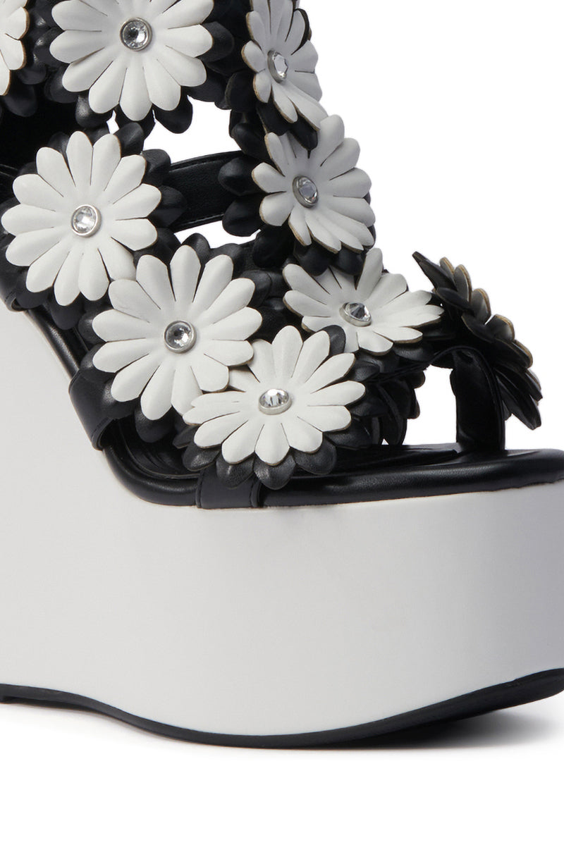 The AZALEA WANG FLOWER EMBELLISHED WEDGE SANDAL IN BLACK features black and white floral appliques with silver studs, a thick white wedge heel, and a black trim at the bottom edge.
