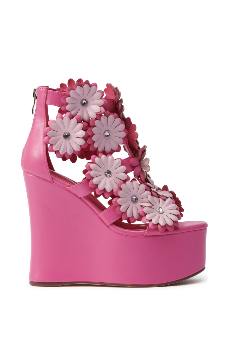 The AZALEA WANG FLOWER EMBELLISHED WEDGE SANDAL IN PINK features bright pink faux leather, multiple pink and magenta 3D floral appliqués with silver stud centers, and a back zipper.