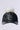 Introducing the TOASTIE FAUX FUR POM HAT: a chic black leather baseball cap with an adjustable strap, adorned with a plush white faux fur pom-pom on top, showcased against a simple light background.