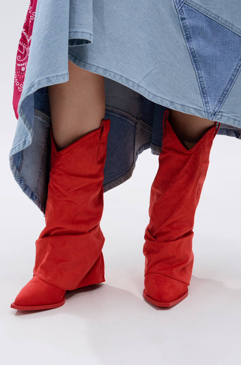 A person wears the AZALEA WANG HAWKSTON RED RUCHED WESTERN BOOTIE with a faux suede upper and chunky heel, paired with a blue patchwork denim skirt featuring a pink bandana detail at the hem, set against a plain light background.