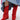 A person wears the AZALEA WANG HAWKSTON RED RUCHED WESTERN BOOTIE with a faux suede upper and chunky heel, paired with a blue patchwork denim skirt featuring a pink bandana detail at the hem, set against a plain light background.