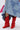 A person in a patchwork denim skirt and AZALEA WANG HAWKSTON RED RUCHED WESTERN BOOTIE with a chunky heel stands on a white background, with a pink bandana tucked under one arm, partially visible.