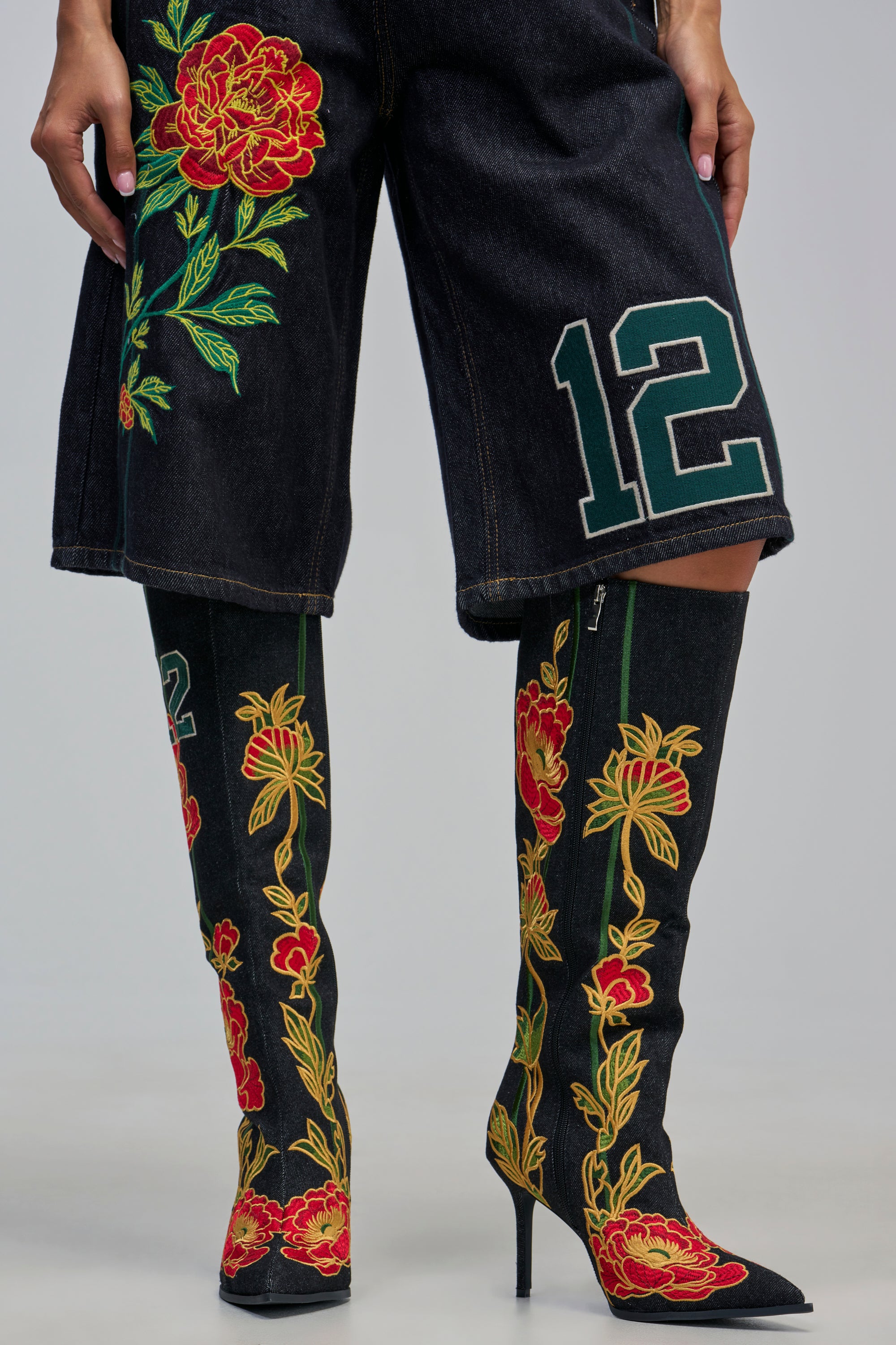 AZALEA WANG HAWN BLACK MULTI FLORAL EMBROIDERED STILETTO BOOT in black denim with vibrant red and green floral embroidery, worn with matching embroidered denim shorts.