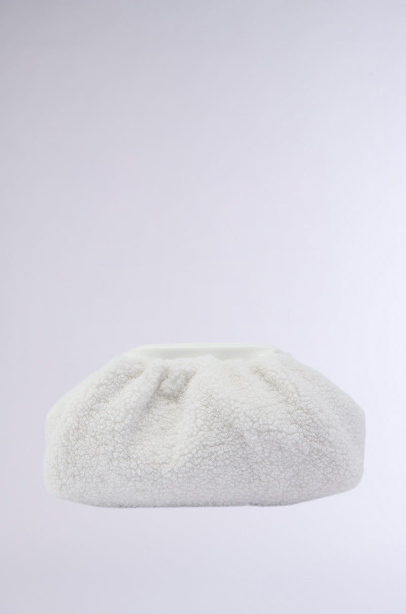 Introducing the ESSENTIAL SHERPA CLUTCH: a soft, textured white clutch bag featuring a gathered, rounded shape. Crafted from plush, faux sherpa fabric, it offers a cozy and fluffy appearance set against a smooth gradient light gray background. The magnetic square frame enhances both elegance and functionality.