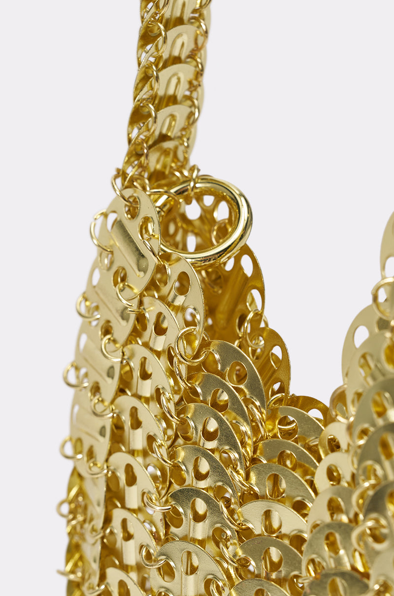 Close-up of the TAYTAY METAL PURSE featuring linked, shiny gold metal discs with circular cutouts, connected by small rings. The purse’s intricate, reflective design emphasizes its textured and sculptural evening bag finish. 4