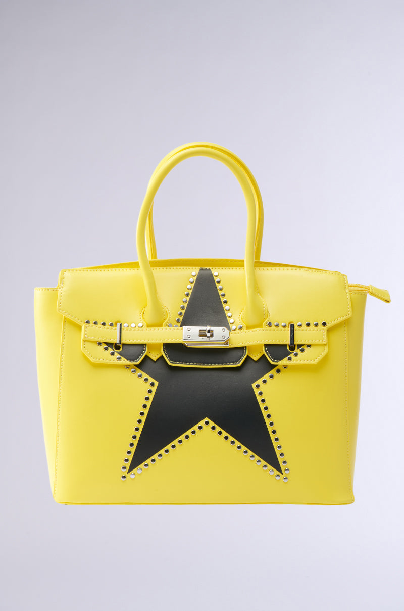 The STAR POWER TOTE is a structured bright yellow faux leather handbag with a black star design, front silver studs, two handles, and a silver clasp on the flap closure.
