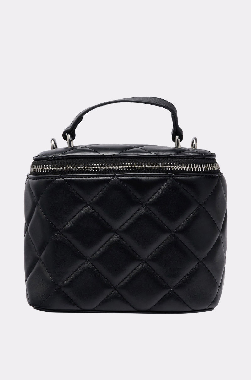 The IN PARIS QUILTED PURSE, in black with a top handle and silver zipper closure, features a sleek chain strap and is displayed against a plain light gray background. 0
