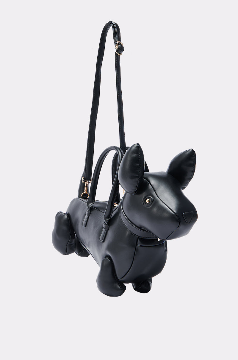 The BARK BACK PU DOG PURSE features a playful dog-shaped silhouette with pointed ears, short legs, and a long shoulder strap, crafted from faux leather and displayed against a plain light backdrop.