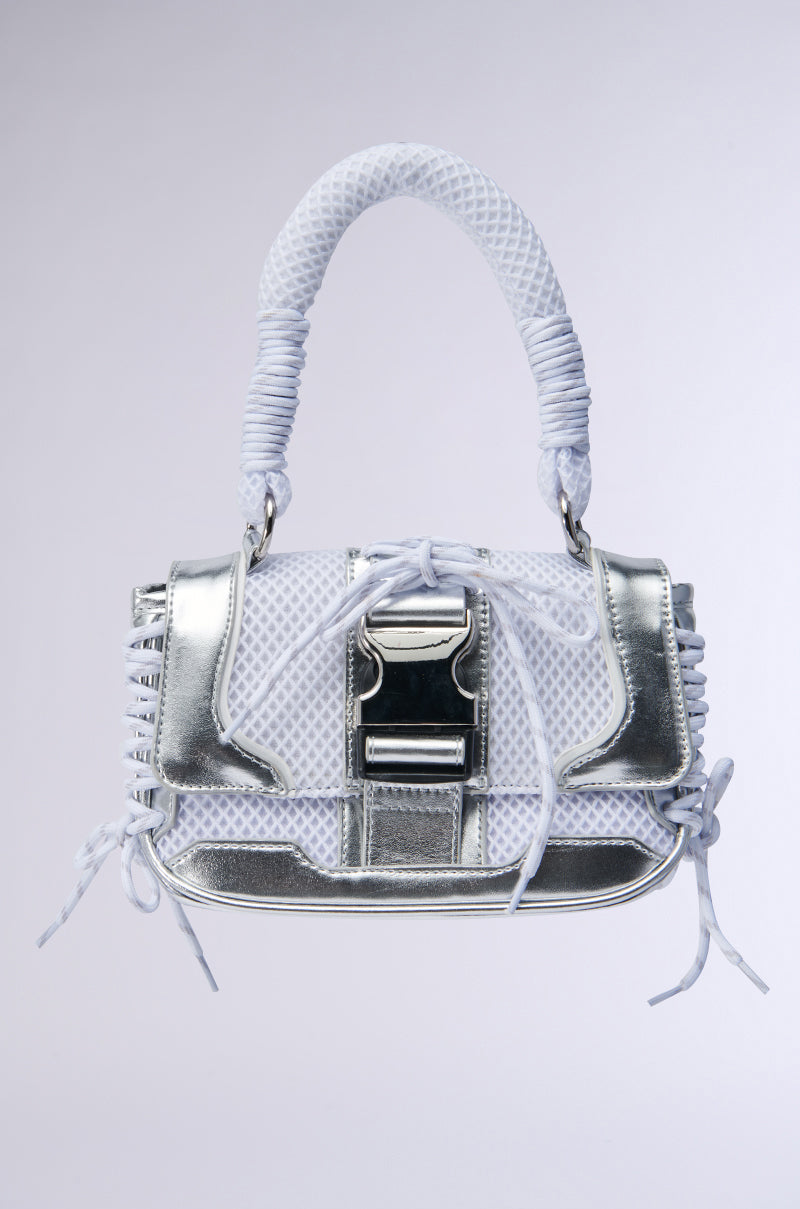 The LACED UP SNEAKER PURSE is a chic and modern handbag crafted from metallic faux leather with a textured white and silver design. It features a woven handle, sporty mesh detailing, decorative stitches along the edges, and is accented with a large metallic buckle on the front.