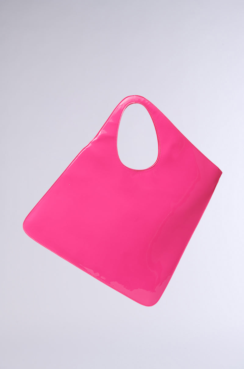 A vibrant pink, glossy CHECK ME OUT PURSE from the AKIRA Label features a curved handle and minimalist design, crafted from faux patent leather, set against a plain gray background. 0