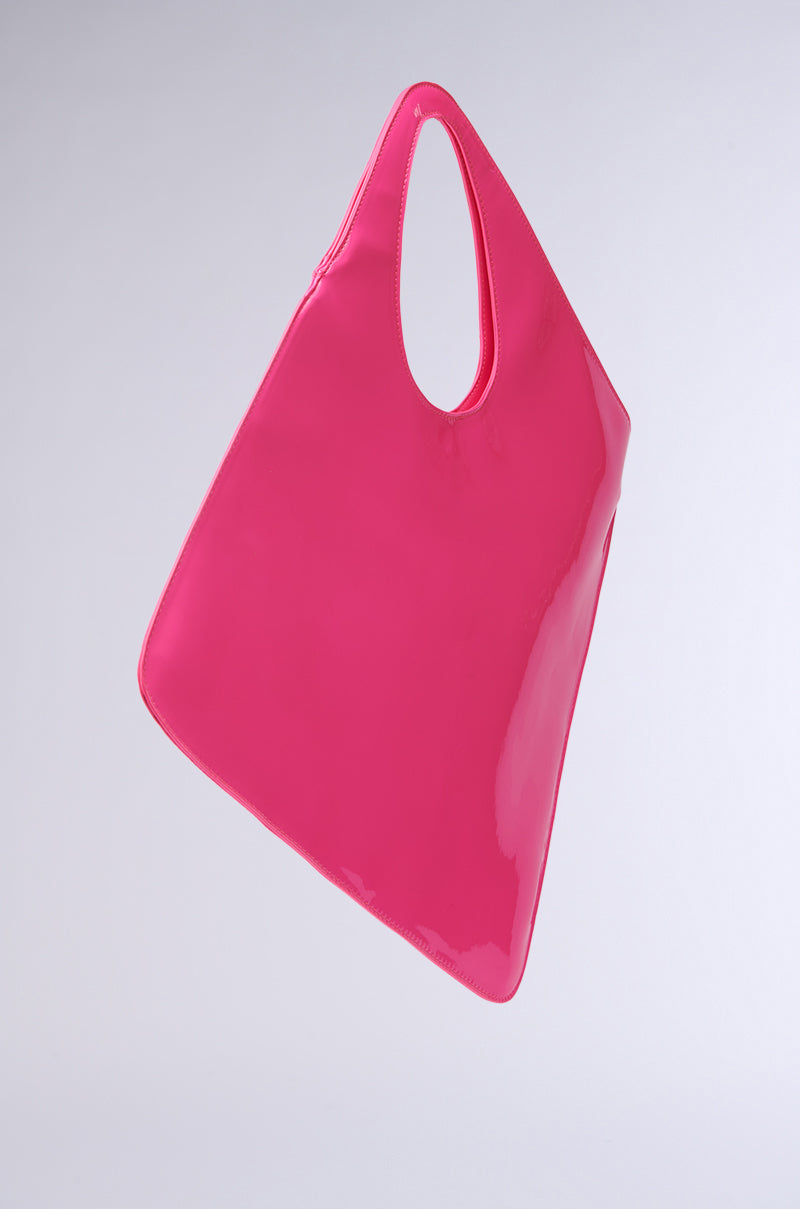The AKIRA Label CHECK ME OUT Purse, crafted from shiny pink faux patent leather, is elegantly suspended in mid-air against a plain background. This sleek geometric purse features a triangular silhouette and a slim, curved top handle. 3