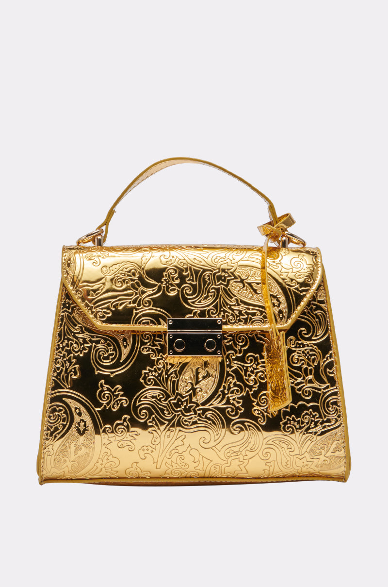 The CHROME LIFE PURSE is a shiny gold handbag featuring an embossed floral pattern, top handle, and decorative lock with tassel detail on the front. 1