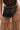 A person wears a sheer brown polka-dot skirt with a black belt and the JACKY BELT BAG by AKIRA Label attached, paired with a sheer, structured black bodice.