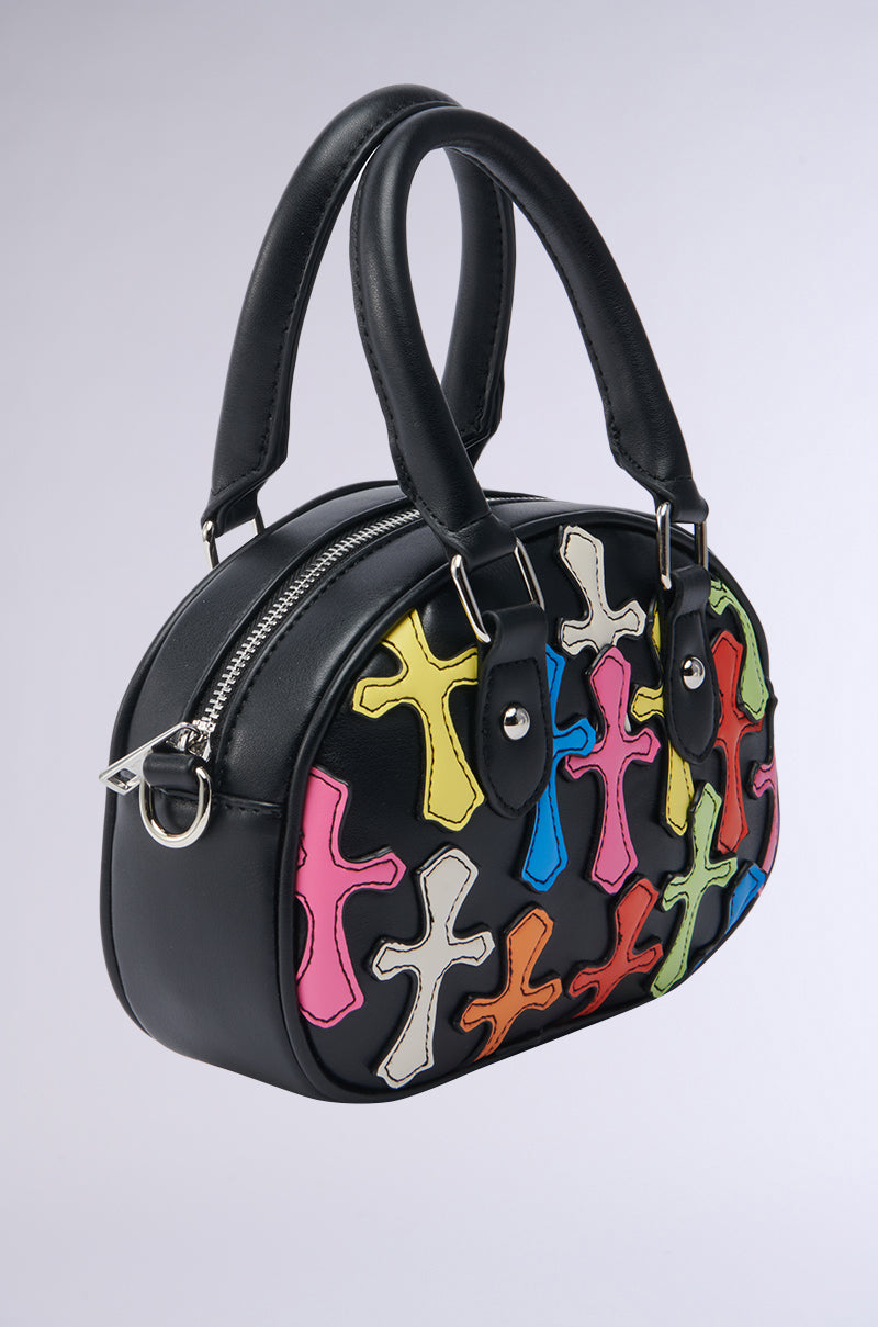 The CROSS ME PATCH PURSE is a stylish faux leather handbag with two handles, featuring colorful cross-shaped patches—pink, yellow, blue, green, and white—on its side for a playful look. 5
