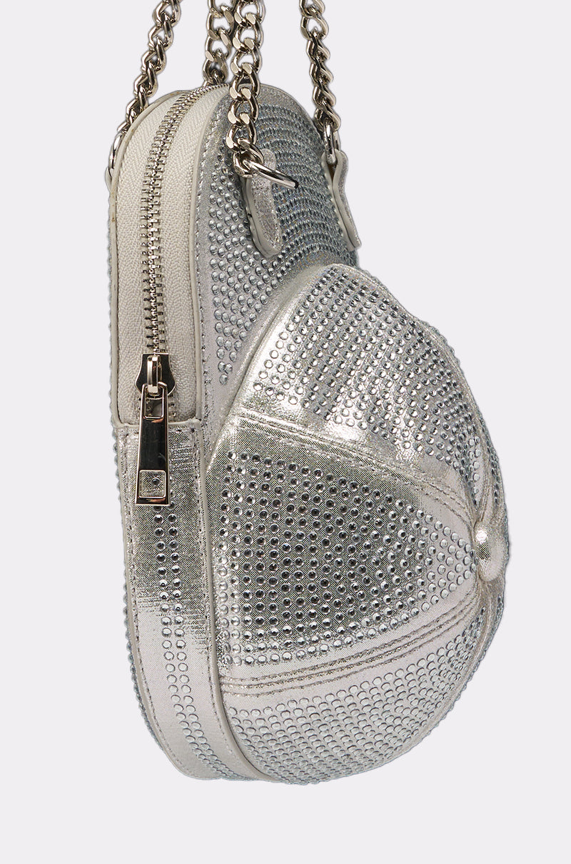 The NO CAP BLING PURSE is a metallic silver, baseball cap-shaped purse adorned with sparkling rhinestones, featuring a shiny zipper and a chic chain strap. 3
