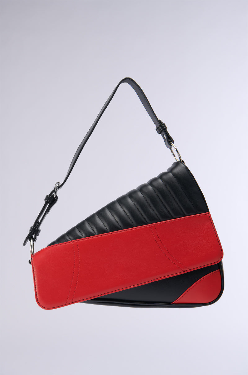 The DIDI LOVES ME PU PURSE by AKIRA Label exudes style with its modern asymmetrical color block design. The upper section boasts quilted black material, while the lower part features smooth red faux leather accented by black corners. A black strap embellished with silver hardware completes this chic handbag.