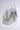 The STAY BLESSED SPIKE PURSE is a fashion-forward white faux leather handbag, decorated with large silver spikes and multiple silver chains, displayed against a plain light gray background.