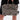 A person holds the TRY ME EMBELLISHED TOTE featuring zebra print, metallic spikes, and stud details, paired with a black outfit; focus is on the bag and hands against a plain background.