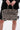 A person holds the TRY ME EMBELLISHED TOTE featuring zebra print, metallic spikes, and stud details, paired with a black outfit; focus is on the bag and hands against a plain background.