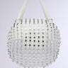 A white faux leather handbag with a spherical shape and two sturdy handles, the STAY BACK SPIKE BASKETBALL BAG is adorned with rows of silver and black metal studs, creating a striking, textured design against a plain light gray background.