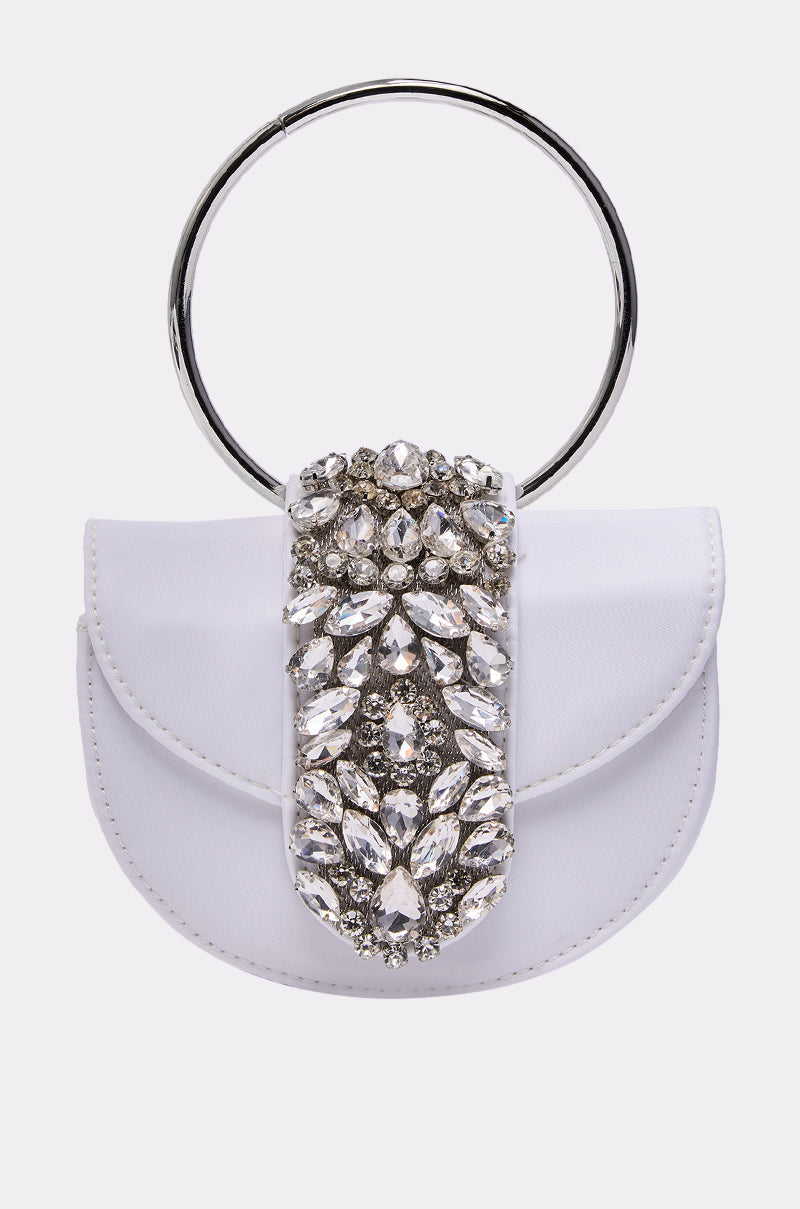 The TO THE EVENT EMBELLISHED PURSE is a small white bag with a large silver ring handle and a front flap featuring sparkling crystal floral embellishments—perfect for adding elegance to your event look.