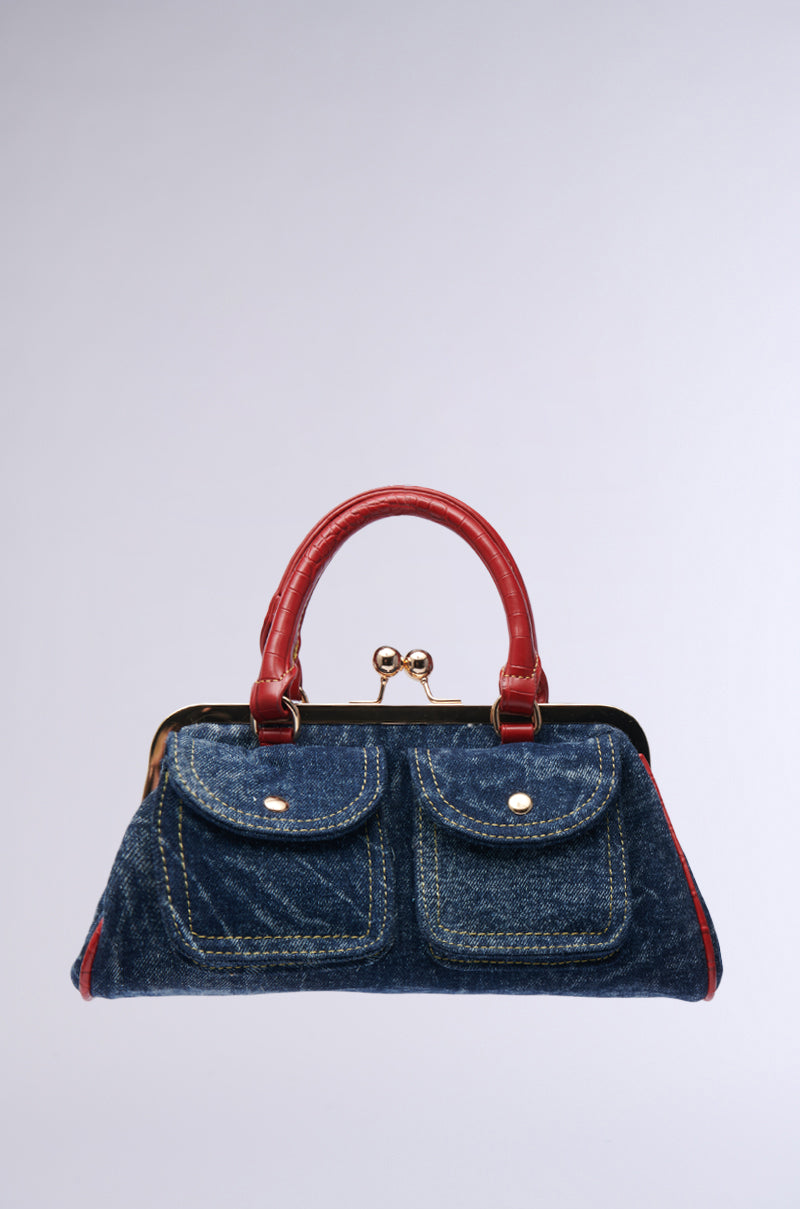 Introducing the ON THE FLIGHT CARGO COIN PURSE - a denim handbag adorned with striking red leather handles and trim. It features two front pockets and a stylish clasp closure crafted from faux crocodile leather, set against a plain light gray backdrop.