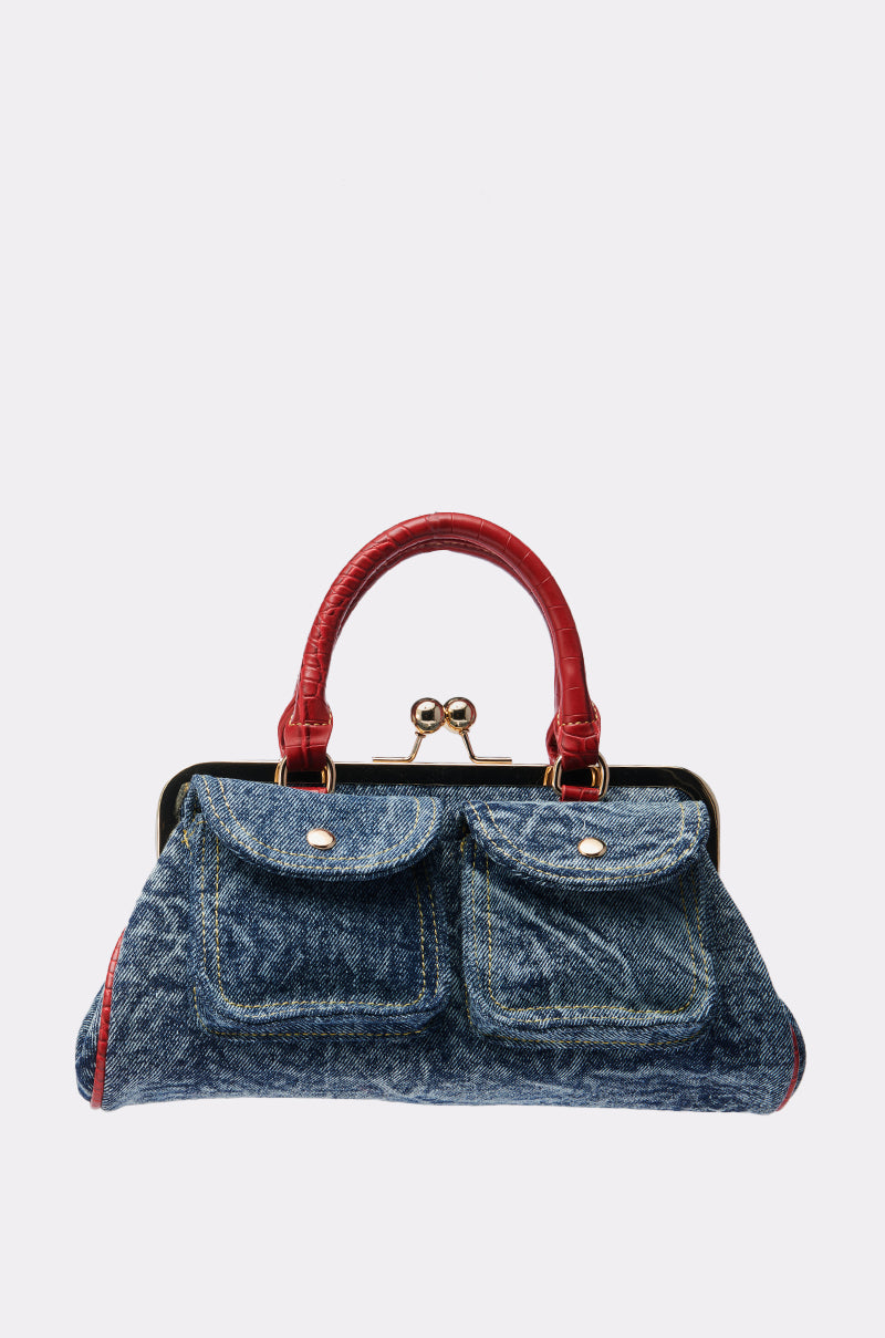 The ON THE FLIGHT CARGO COIN PURSE is a blue denim coin purse with cargo-style pockets, red leather handles, and a gold-tone metal frame and clasp, shown against a plain white background.