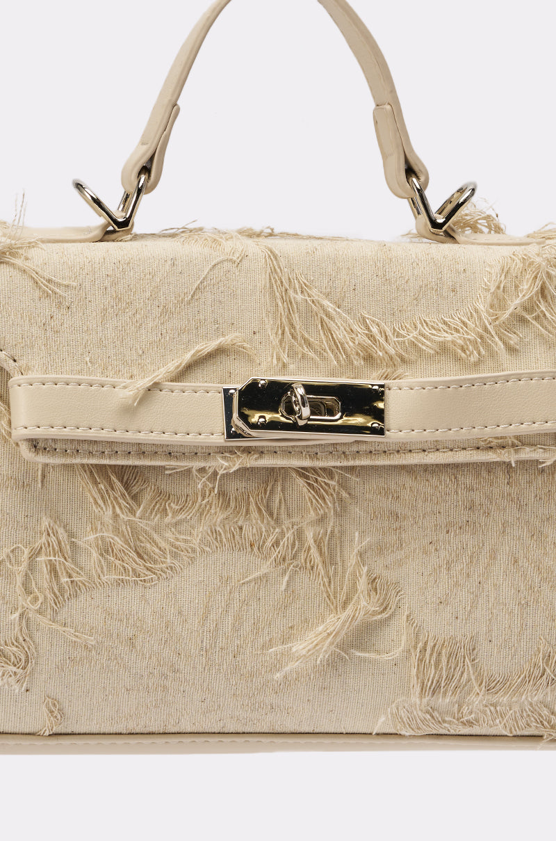 A close-up of the OFFICE SIREN IVORY PURSE with a frayed beige fabric texture, top handle, and a gold-tone buckle closure on the front. 3