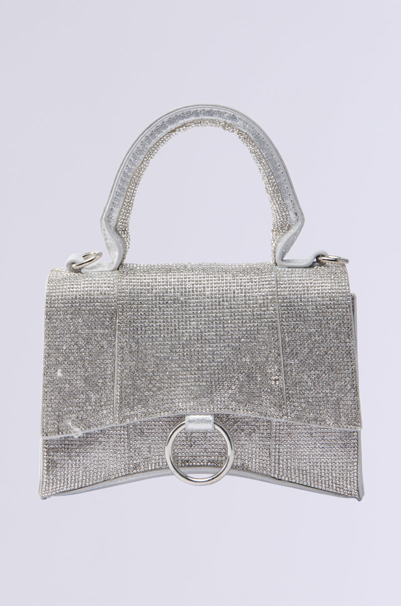 A glittery silver BLING PURSE adorned with rhinestones, featuring a textured surface, a short handle, and a decorative circular metal ring at the front. 0