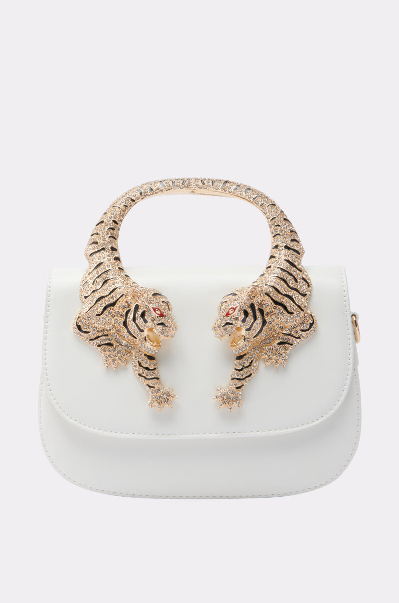 The LUXE LIFE PURSE is a white handbag with a gold handle shaped like two intricately detailed tigers facing each other, featuring striking red gemstone eyes.