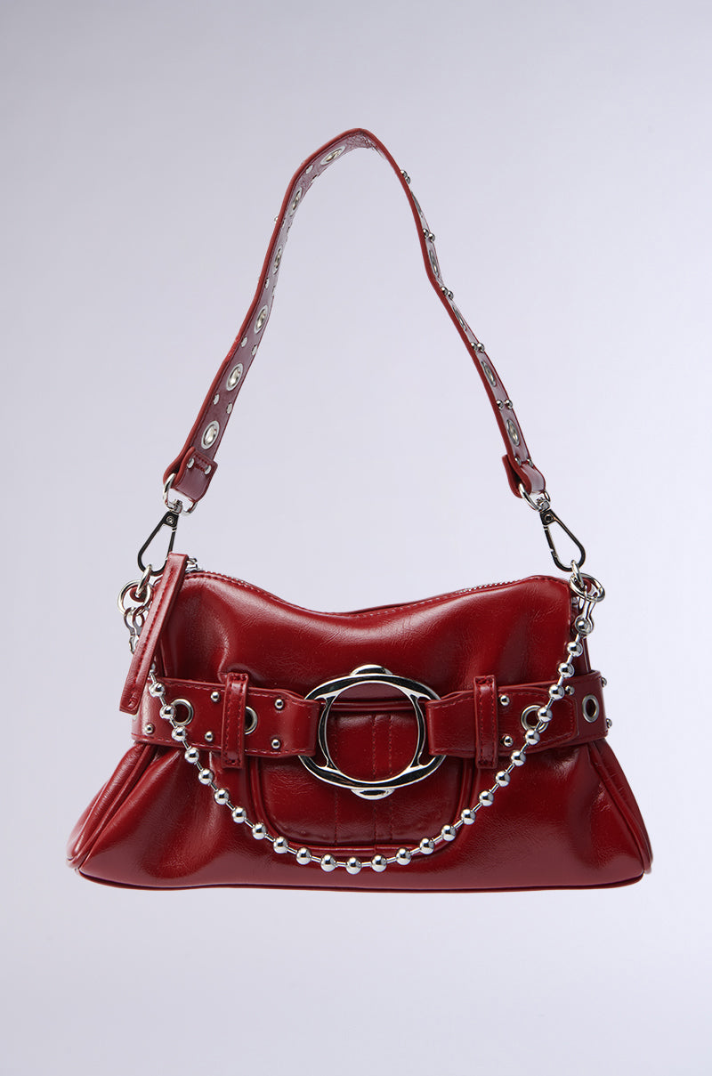 The RED HOT PU BAG is a shiny red structured handbag with a silver buckle, decorative belt, and a strap featuring silver grommets and chain detailing, shown on a light gray background.