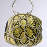 The MY STANDARD SNAKE BAG is a vegan leather handbag with a vibrant yellow snakeskin pattern and black accents. It features silver chains with circular metal rings, metallic chain details, and a unique handle of two intertwined metal hoops.