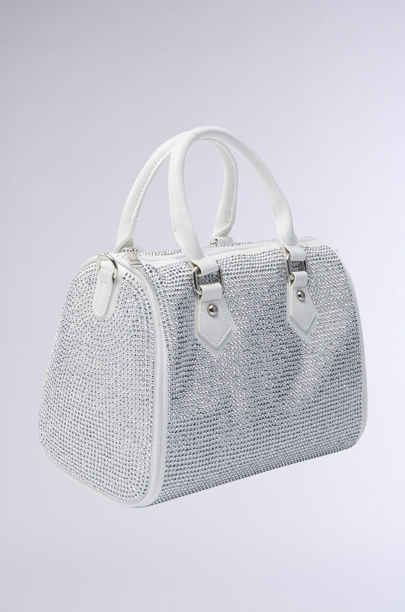 The BLING BOWLER BAG features a silver, rhinestone-studded design with white handles, trim, metallic hardware accents, and a detachable shoulder strap. Shown on a light grey background for versatile styling. 2