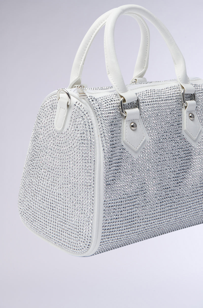 The BLING BOWLER BAG is a white handbag adorned with silver rhinestones, featuring two short handles, a detachable shoulder strap, and silver hardware, shown on a plain light gray background. 3