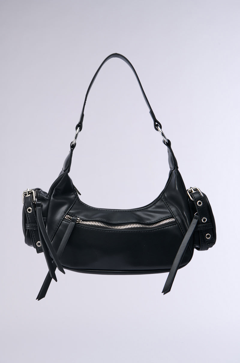 The THAT'S IDEAL PU PURSE is a stylish black faux leather bag, adorned with metallic zipper detailing and adjustable straps. Its design showcases side pockets with grommet accents and a curved shape, set against a plain gray background.
