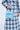 A person in a blue and black checkered coat is holding the WORTH IT ALL FEATHER PURSE—an opulent, fluffy blue handbag adorned with rhinestones.