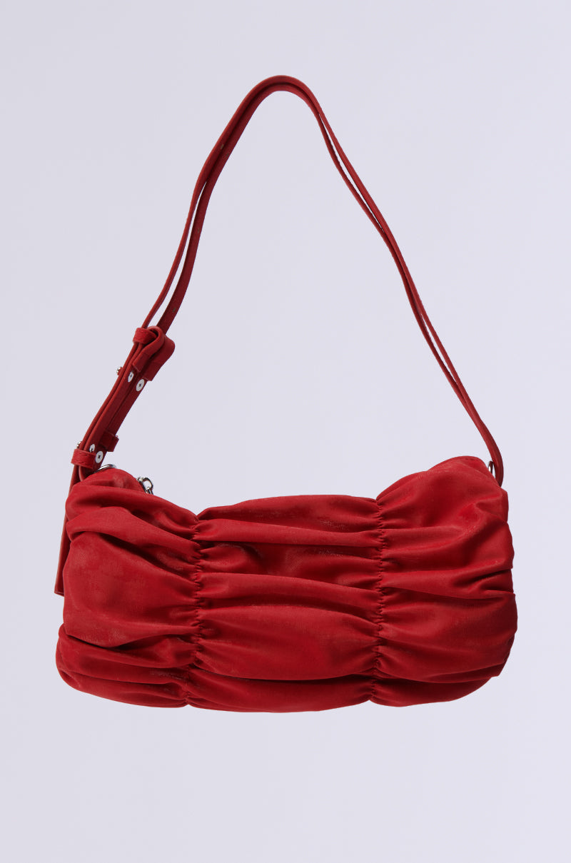 The HOT TAMALE RUCHED PURSE is a faux leather handbag with a striking ruched design, silver hardware, and an adjustable strap, elegantly displayed against a white background.