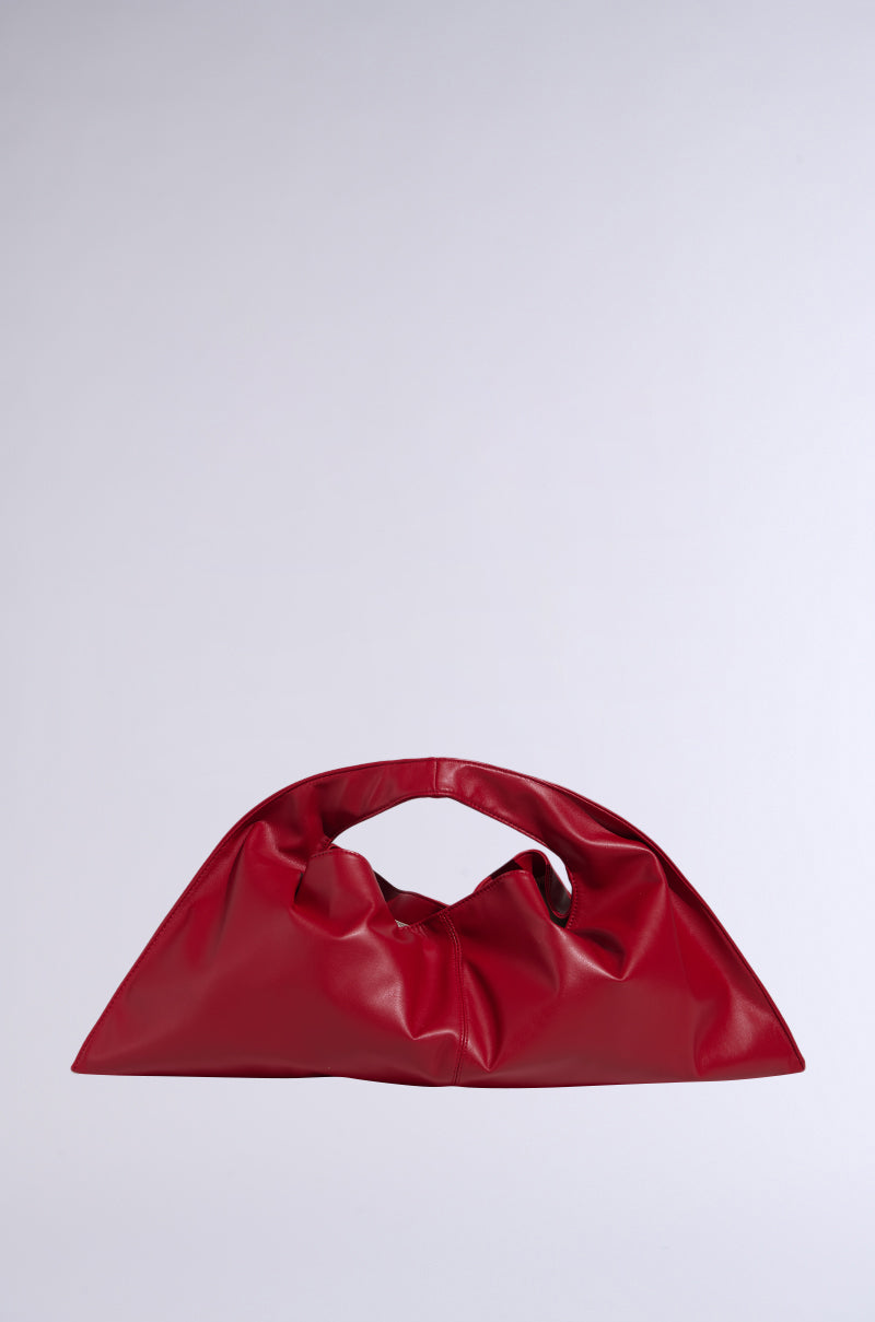 The CREATE DRAMA OVERSIZED TOTE is a bright red, soft faux leather bag with a ruched handle and slouchy triangular shape. It has a spacious interior and is shown against a plain light grey background.