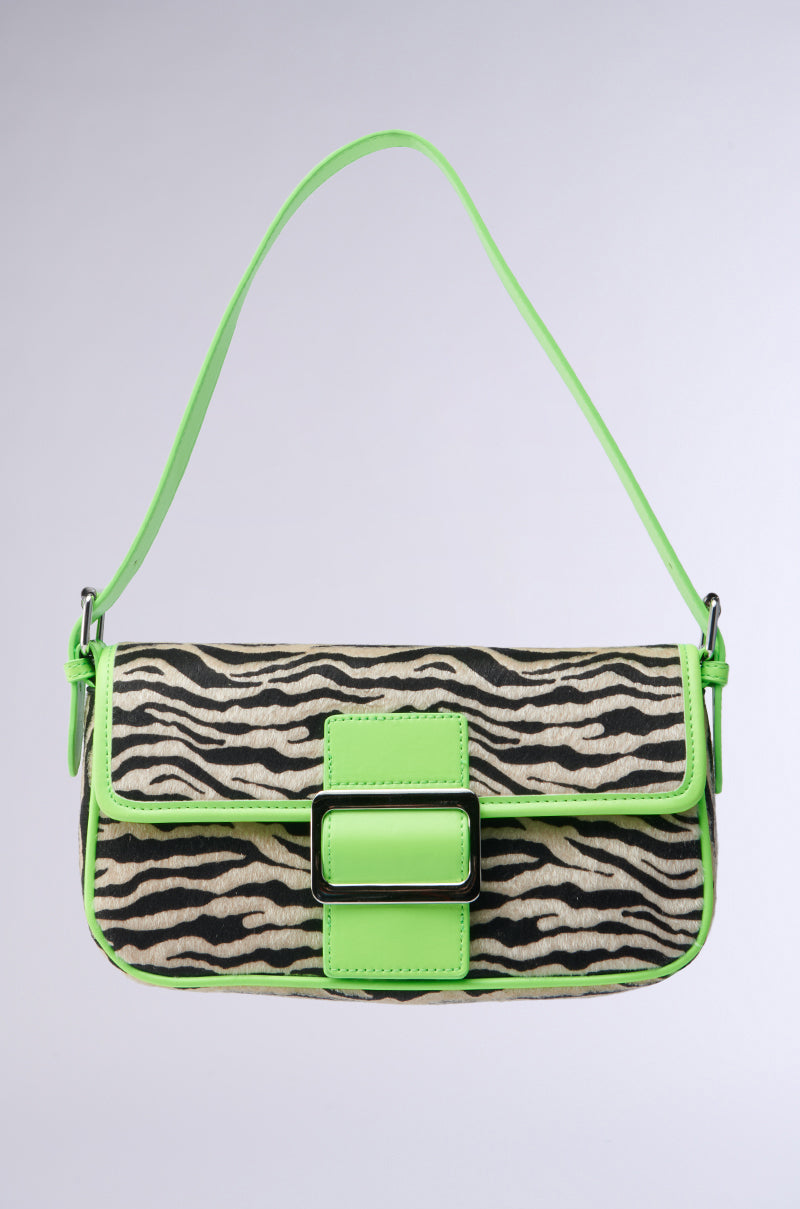 The I LIKE IT WILD ZEBRA BAG is crafted from faux pony hair with a zebra print, neon green strap, lime green trim, and a matching front buckle, all displayed against a light gray background.