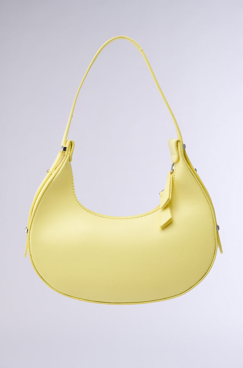The GET WITH THE TREND PU PURSE is a yellow crescent silhouette handbag made from faux leather, featuring a single shoulder strap and a small tag, shown against a plain light gray background.