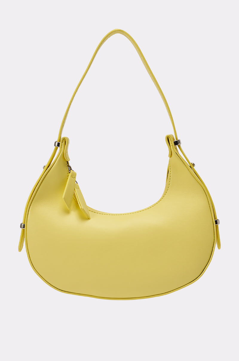The GET WITH THE TREND PU PURSE is a pastel yellow crescent silhouette bag made from faux leather, featuring a single curved strap and zipper closure, shown against a plain white background. 2