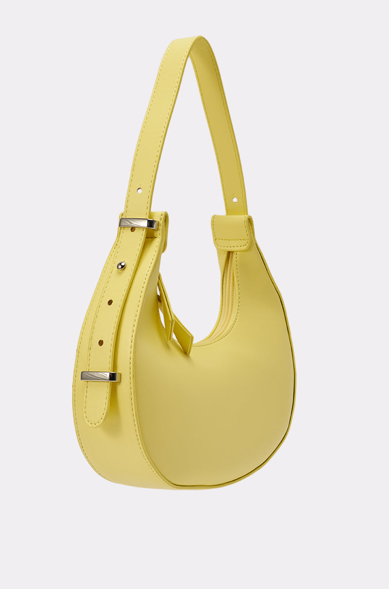 The GET WITH THE TREND PU PURSE is a yellow crescent silhouette bag with an adjustable strap and silver buckle, made from faux leather, shown against a plain white background. 3